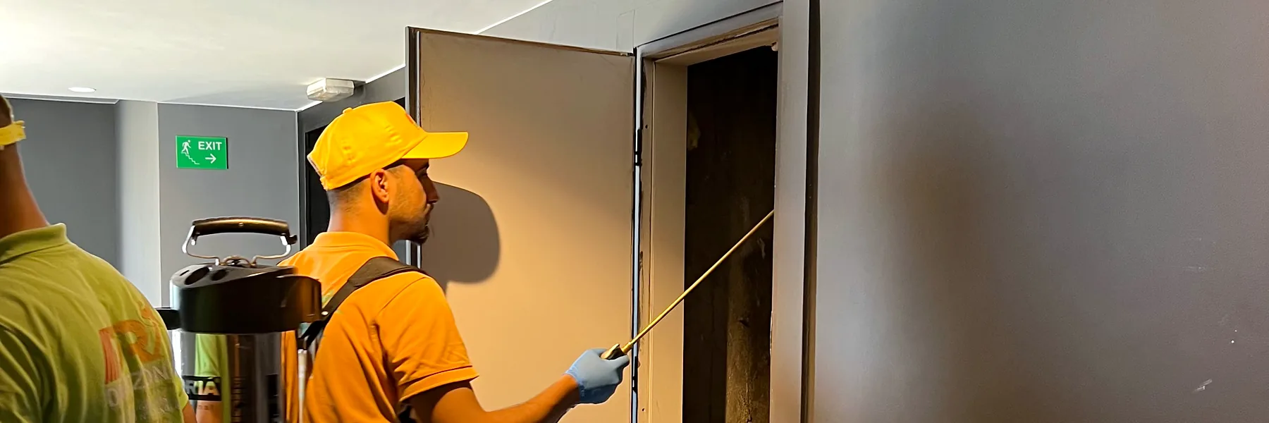 Un technicien Deratizon traite une trappe de visite dans le couloir d’un hôtel.